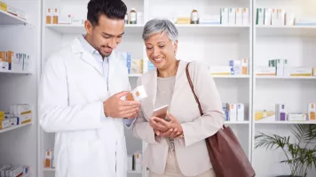 Imagen de un farmacéutico y una paciente anciana mirando un producto