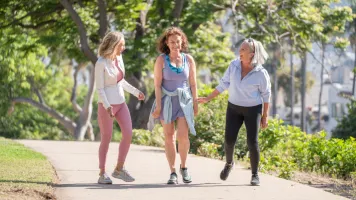 Tres mujeres charlando mientras pasean por un parque.