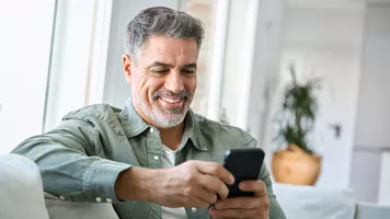 hombre de mediana edad sonriendo mirando el teléfono