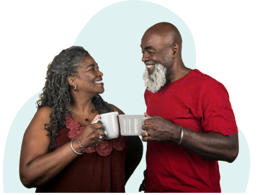 La pareja afroamericana en los bajo 60 vestidos de rojo, sonriendo y mirándose mientras chocan sus tazas
