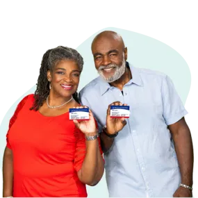 Pareja afroamericana sonriendo y sosteniendo tarjetas de Medicare