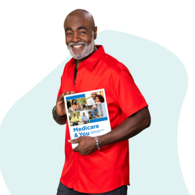 Hombre afroamericano caminando, sonriendo y sosteniendo una copia del Manual Medicare y usted