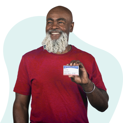 Una mujer afroamericana en los bajos 60 con una blusa roja sosteniendo una tarjeta de Medicare